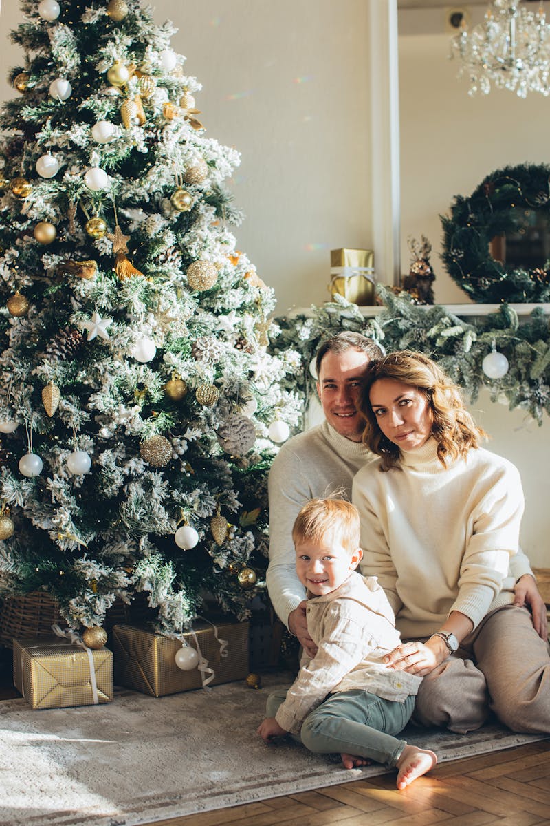 A family sits together by a beautifully decorated Christmas tree with gifts.